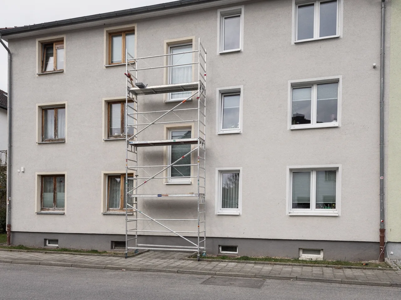 Edificio residenziale durante la sostituzione delle finestre: a sinistra ancora le vecchie finestre in legno, a destra le nuove finestre bianche in PVC già montate