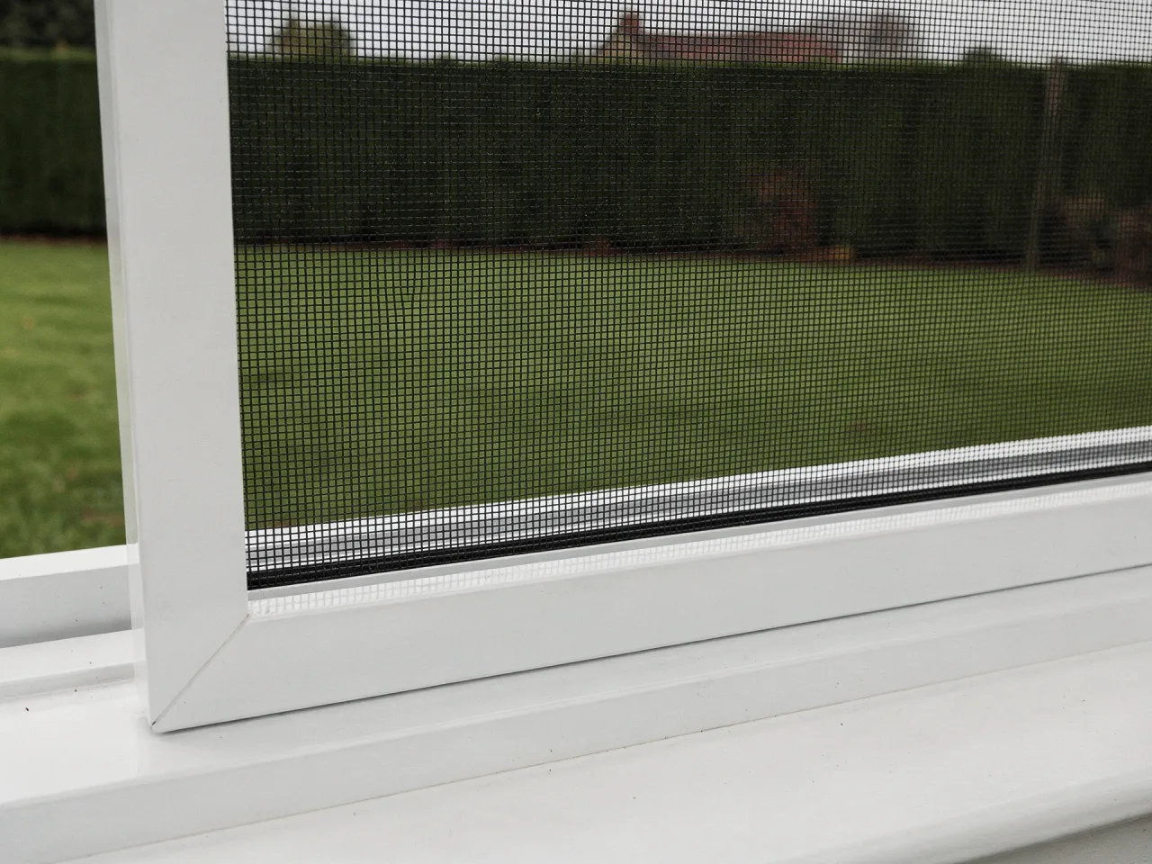 White aluminium insect screen frame in a window reveal, close-up of the mesh